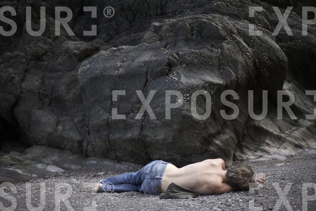 Boy asleep on shingle beach