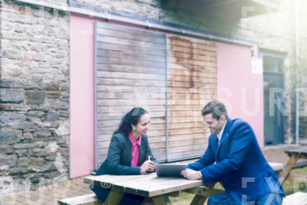 Two Businesspeople Sat On Picnic Table In Meeting