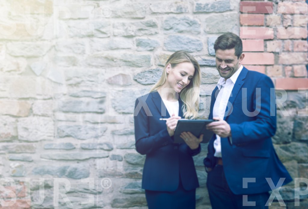 Two Businesspeople Stood Outside Stone Office Having Meeting