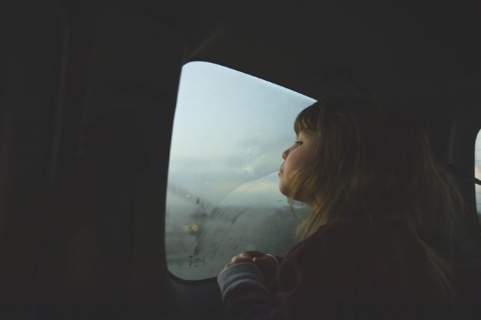 Girl looking out of car window at dusk