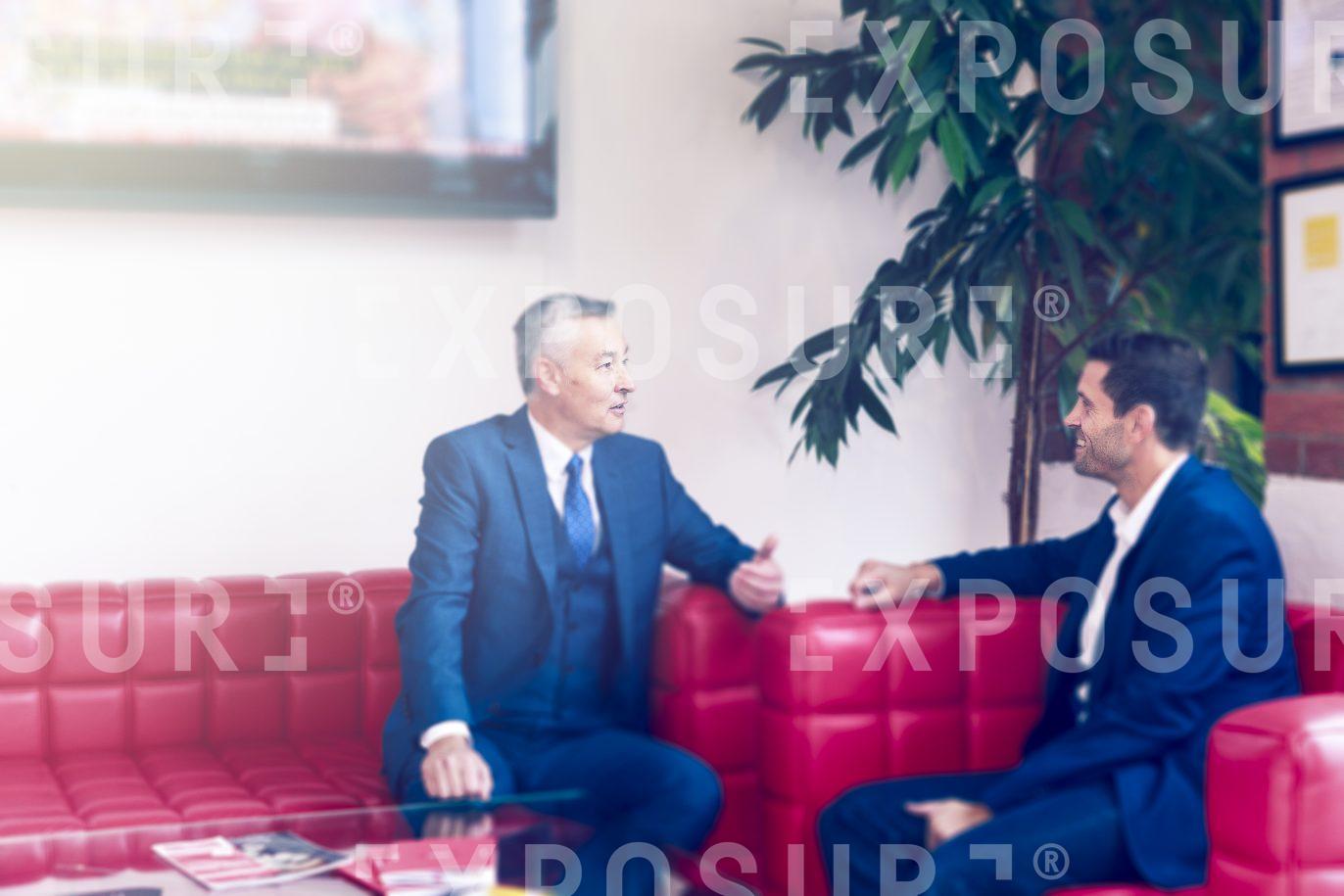 Two Businessmen Chatting On Sofa