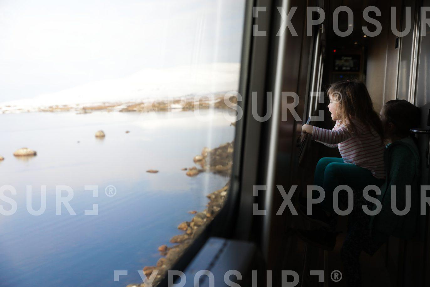 Girl looking out onto winter Highland landscape from train window