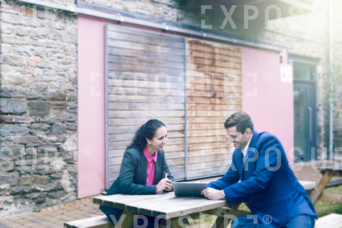 Two Businesspeople Sat On Picnic Table In Meeting