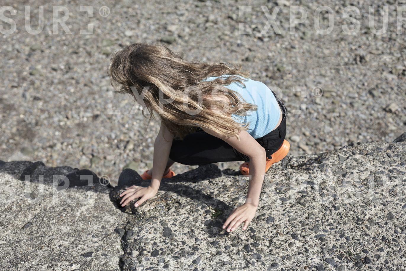 Girl climbs on beach wall