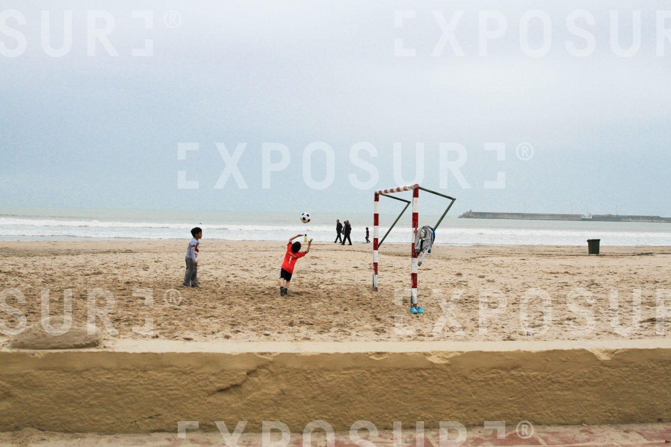 Kids playing football on beach