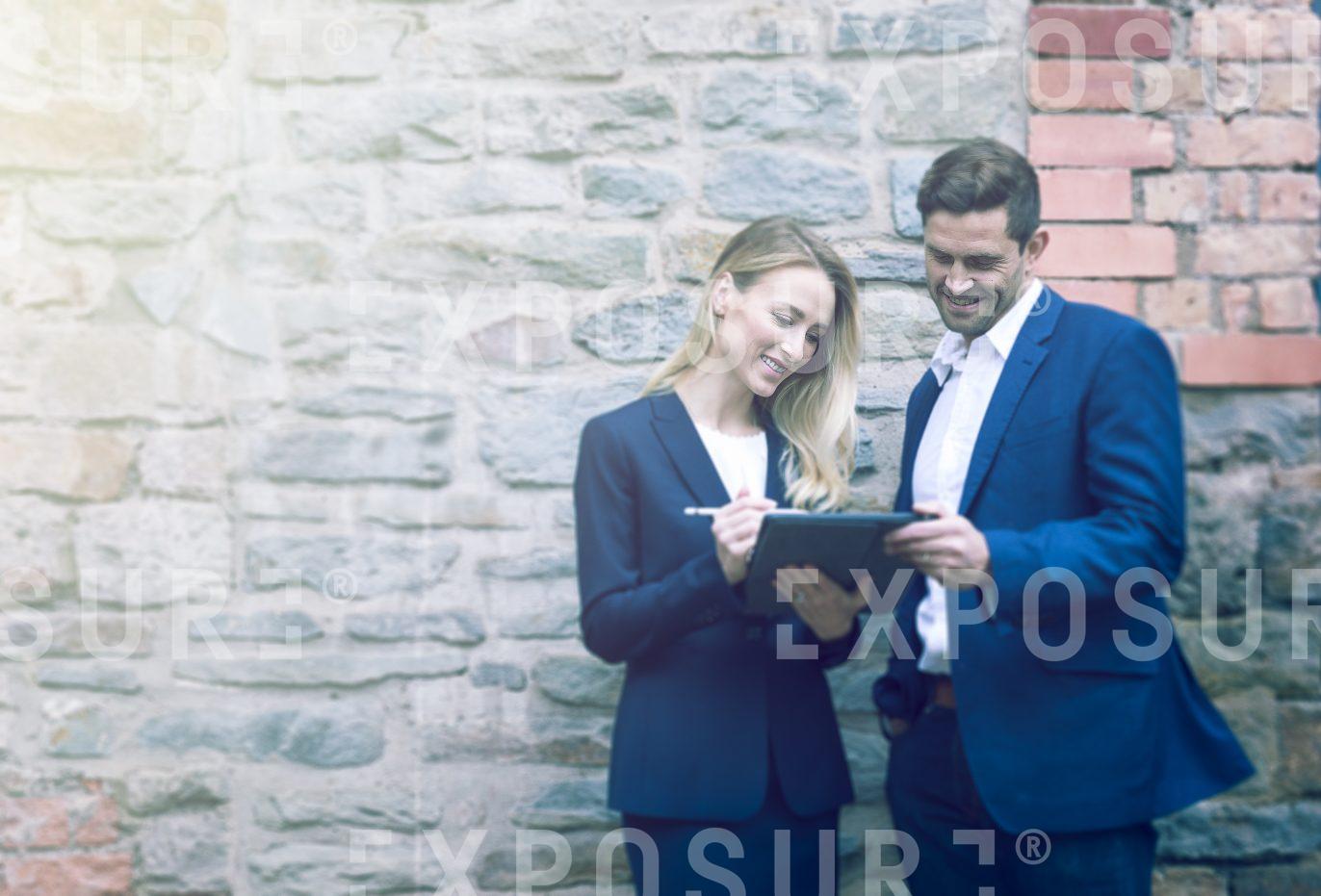 Two Businesspeople Stood Outside Stone Office Having Meeting